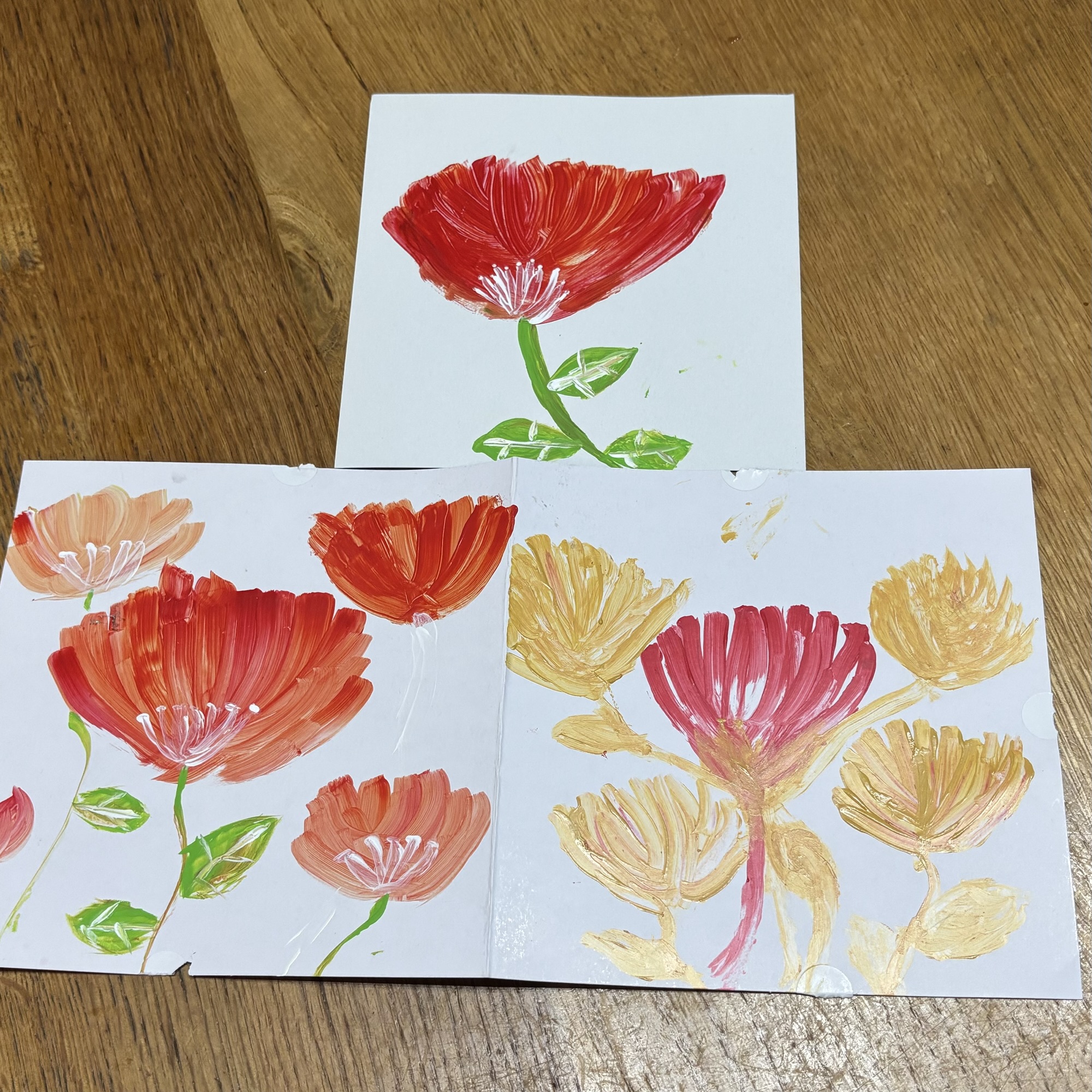 赤やオレンジ、金色で描かれた子どもの花の絵。自由な感性に心が動く。