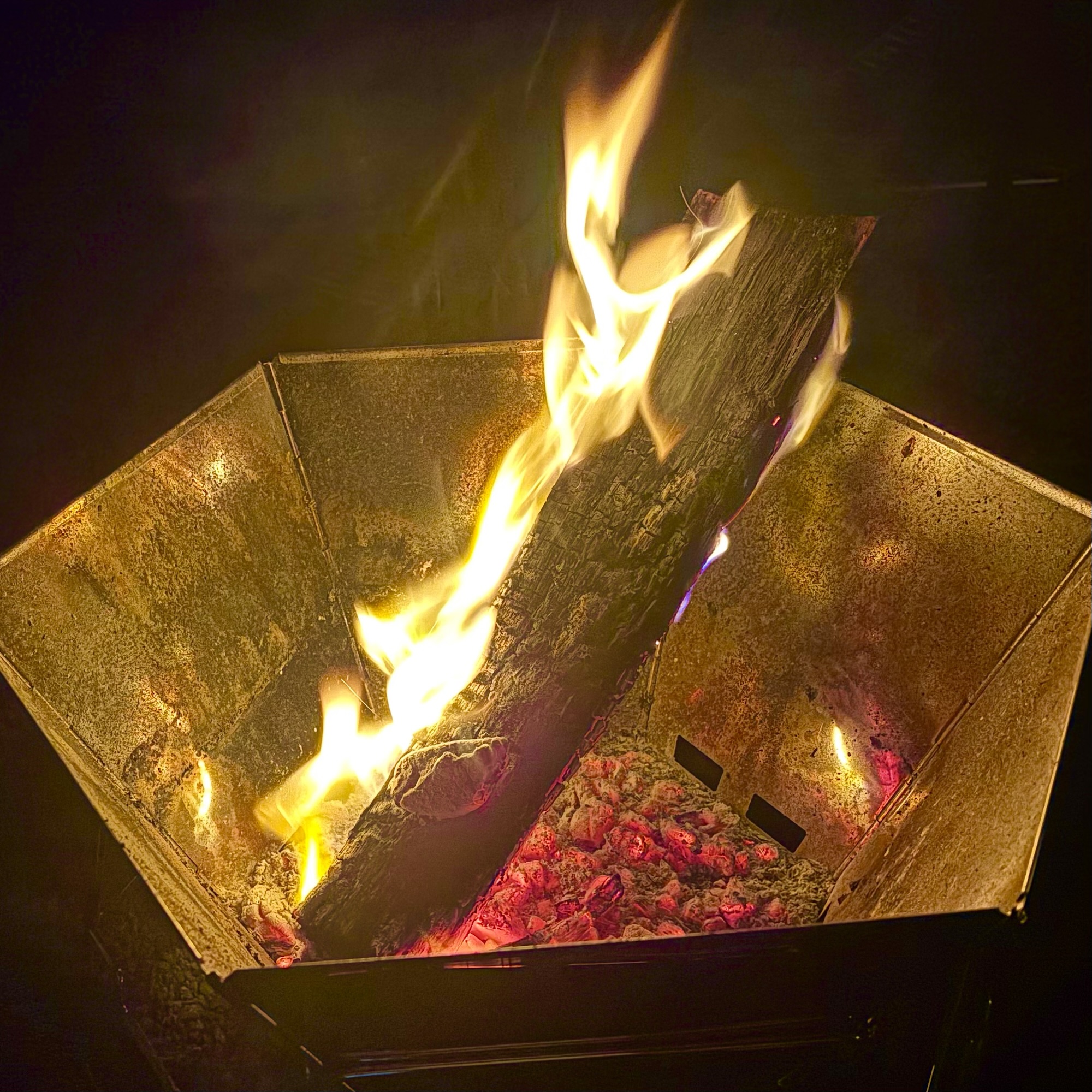  焚き火台の上で大きな薪が燃えている様子。